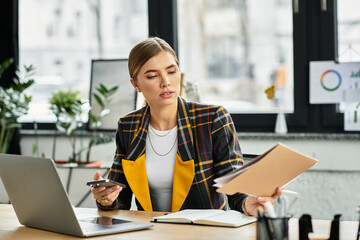 Focused young woman in checkered blazer juggles tasks while working in a bright office space.