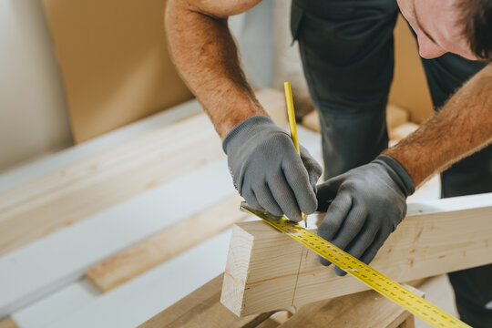Close up of carpenter measuring wooden board using tools in his workshop