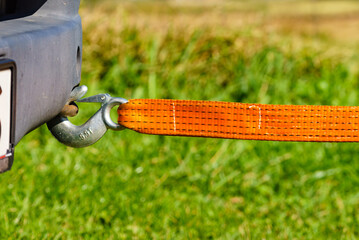 Fototapeta premium Tow hook with orange strap on car. Towing equipment.