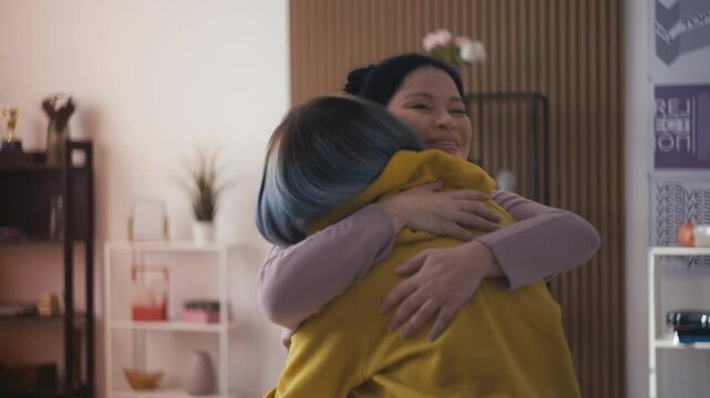 Middle-aged Asian woman hugs her teen daughter, trusting and loving relationship