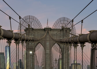 Fototapeta premium Brooklyn Bridge close up detail looking up at suspension cables at sunrise (beautiful landmark travel tourism destination in NYC) iconic New York City attraction over east river downtown Manhattan USA