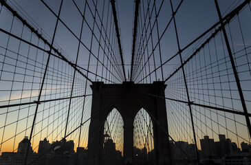Obraz premium Brooklyn Bridge close up detail looking up at suspension cables at sunrise (beautiful landmark travel tourism destination in NYC) iconic New York City attraction over east river downtown Manhattan USA