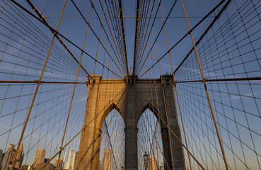 Brooklyn Bridge close up detail looking up at suspension cables at sunrise (beautiful landmark travel tourism destination in NYC) iconic New York City attraction over east river downtown Manhattan USA