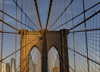 Fototapeta premium Brooklyn Bridge close up detail looking up at suspension cables at sunrise (beautiful landmark travel tourism destination in NYC) iconic New York City attraction over east river downtown Manhattan USA
