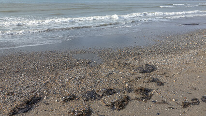 Fuel oil on a sandy beach. The spill of fuel oil in the sea leads to the death of animals and environmental pollution. An environmental disaster. Pollution of nature.
