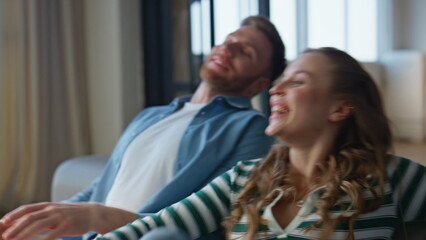 Closeup carefree pair falling sofa having fun at home. Smiling spouses embracing