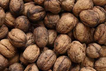 Heap of walnuts in shell, close-up, top view. Healthy eating. Harvest, agriculture. Walnuts, selective focus, background