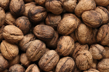 Heap of walnuts in shell, close-up, top view. Healthy eating. Harvest, agriculture. Walnuts, selective focus, background