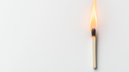 Single glowing matchstick burning with a small flame on a white surface during evening hours