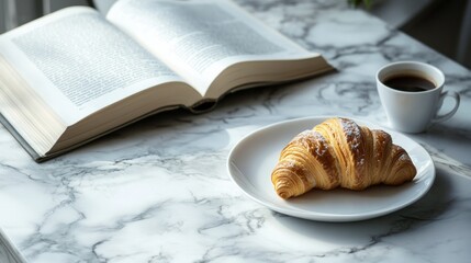 Enjoy a warm, flaky croissant on a white plate accompanied by a cup of coffee next to an open book on a marble table during a peaceful morning