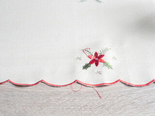 Close-up of an embroidered tablecloth featuring holiday-themed designs, ideal for festive table...