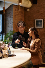 A young couple enjoys a special Valentines Day together over drinks, sharing laughter and love.