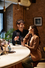 A young couple enjoys a romantic evening, toasting with glasses of wine in a charming restaurant.
