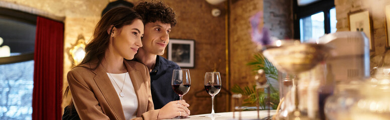 A beautiful couple celebrates their love during a cozy Valentines dinner with glasses of wine, banner