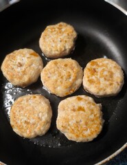 Homemade meat patties with a golden crust are fried in a hot frying pan. Greasy food. frying pan with meat. Vertical