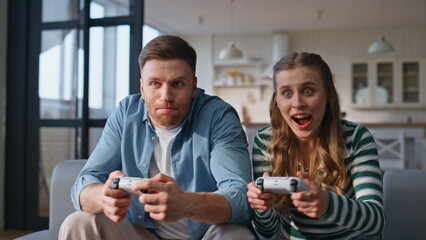 Video players winning game sitting sofa with console at modern home closeup