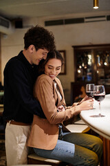 A young couple enjoys a romantic evening together, celebrating their love with wine.