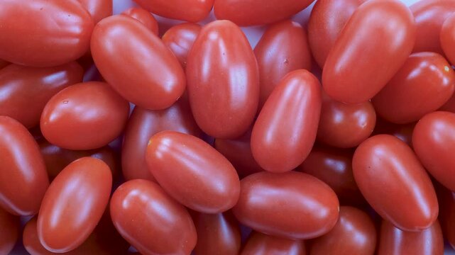 Top down view. Close-up, heap of fresh small tomatoes in close detail. Natural red tones and textured skins. Slider shot. Food, nutrition, vegetables, snacks, ingredient concepts. 4k