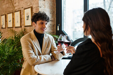 A joyful couple toasts with wine glasses, embracing their love at a cozy restaurant.