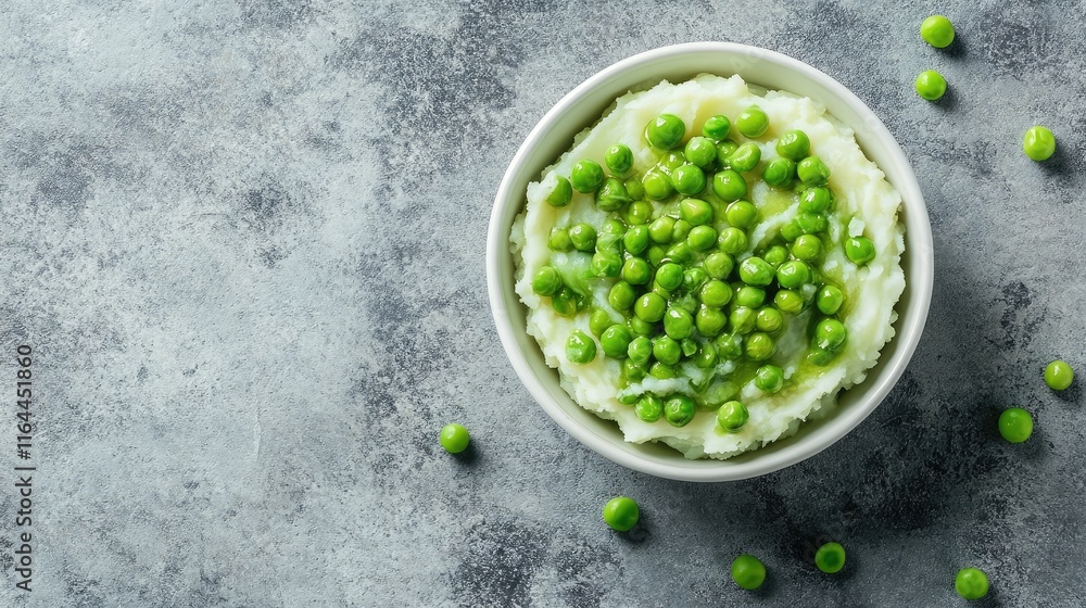 Poster mashed potatoes with fresh green peas in a rustic bowl on textured surface with ample copy space for