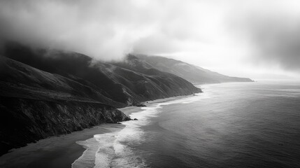 Dramatic black and white coastline of Big Sur with misty mountains and tranquil ocean waves creating a serene coastal landscape