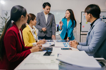 Business team analyzing financial reports using digital tablet and documents, discussing company performance and making strategic decisions in office meeting