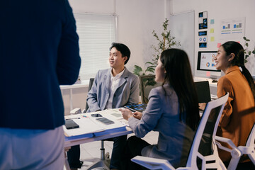 Asian businesspeople attending a briefing in a modern office, listening to their manager explaining a new strategy using charts and reports