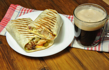delicious appetizing shawarma and a glass of dark beer with foam on the table. selective focus