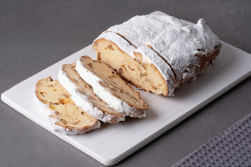 Delicious homemade stollen bread displayed on a wooden board with powdered sugar and chopped nuts