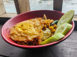 Mie Goreng Close Up, Fried Instant Noodles with Sunny Side Up Egg and Vegetables on Top. Popular Instant Noodles from Indonesia.