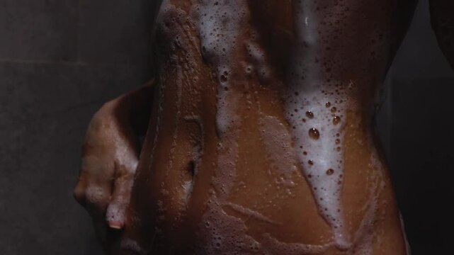 Sensual slender woman washing her belly in shower