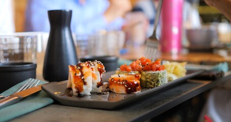 Aesthetics of Japanese cuisine. Stunning close-up of sushi rolls highlights Japanese culinary artistry. Bright ingredients and careful plating make table true showcase of gourmet craftsmanship.