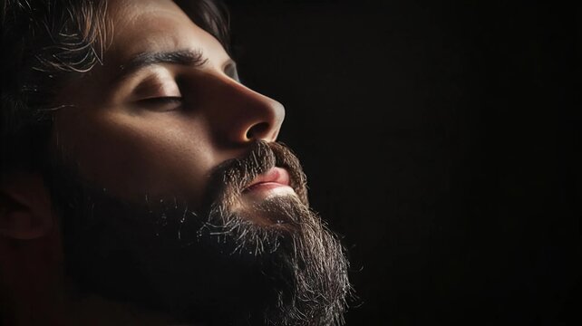 Retrato de hombre con ojos cerrados en fondo negro y con barba arreglada