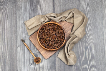 Wooden bowl with coffee beans on wooden background