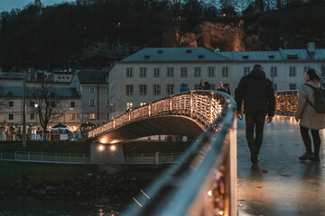 People cross the lock lock bridge decorated for Christmas at night of Salzburg, Austria