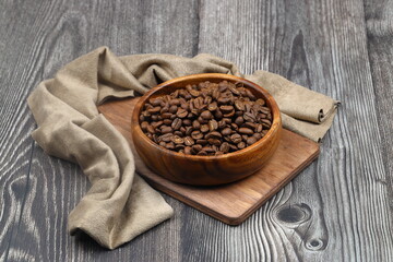 Wooden bowl with coffee beans on wooden background
