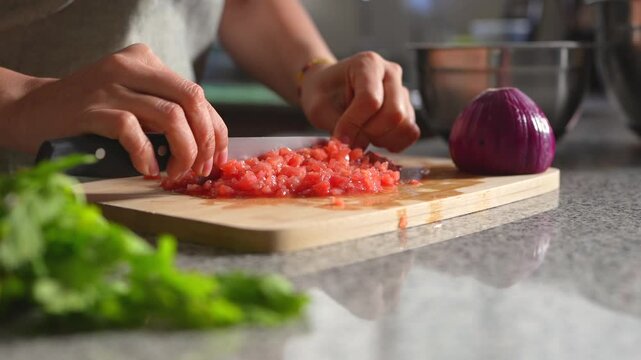 Woman chopping tomato to prepare a guacamole typical of mexico