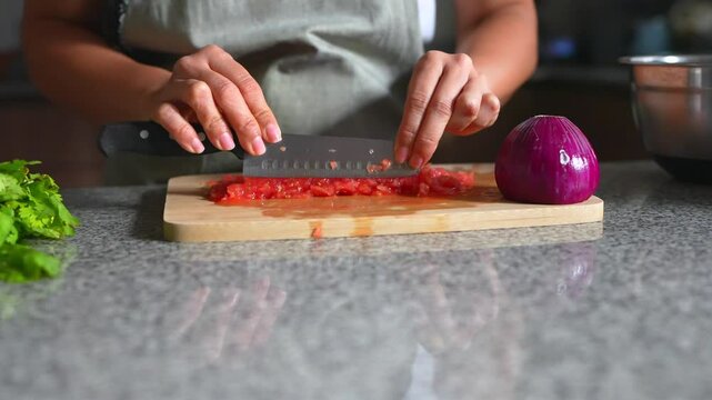 woman chopping tomato to prepare a typical mexican guacamole from the front of the house