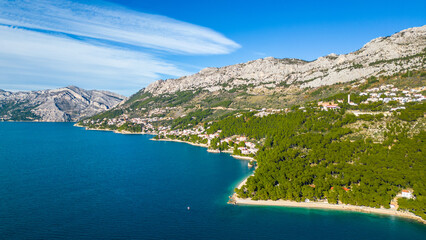 Obraz premium A stunning aerial view of Brela, Croatia, showcasing the iconic Kamen Brela rock formation surrounded by crystal-clear turquoise waters. The coastline is dotted with pristine beaches