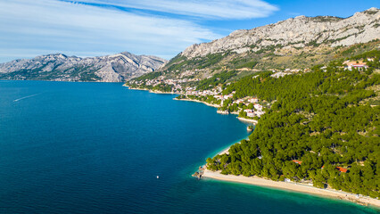 Obraz premium A stunning aerial view of Brela, Croatia, showcasing the iconic Kamen Brela rock formation surrounded by crystal-clear turquoise waters. The coastline is dotted with pristine beaches