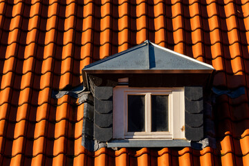 Tiled roof with small dormer window under sunlight in daylight