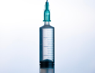 Syringe filled with transparent liquid stands against a light background