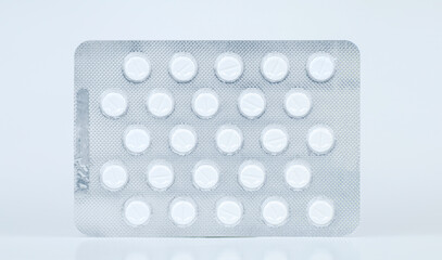 White round pills in blister pack laid on a flat surface