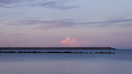 Sunrise on the coast next to the harbor, with the sky illuminated by warm tones. Sardinia