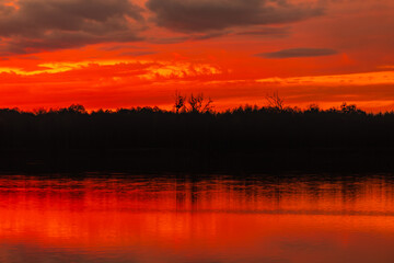 A stunning sunset reflects over serene waters, showcasing vibrant colors and a peaceful atmosphere