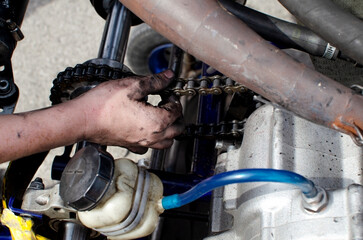 Hands of a boy racer who adjusts the chain on his sports car.