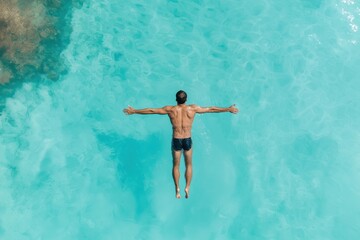 A man is swimming in the ocean with his arms outstretched. The water is blue and calm