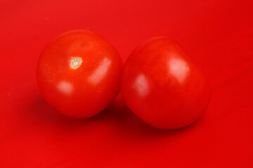 two tomatoes on a red background