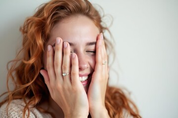 Fototapeta premium Young ginger teen girl smiling and covering her eyes with hands