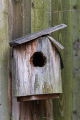 an old bird house hanging from a wooden shad